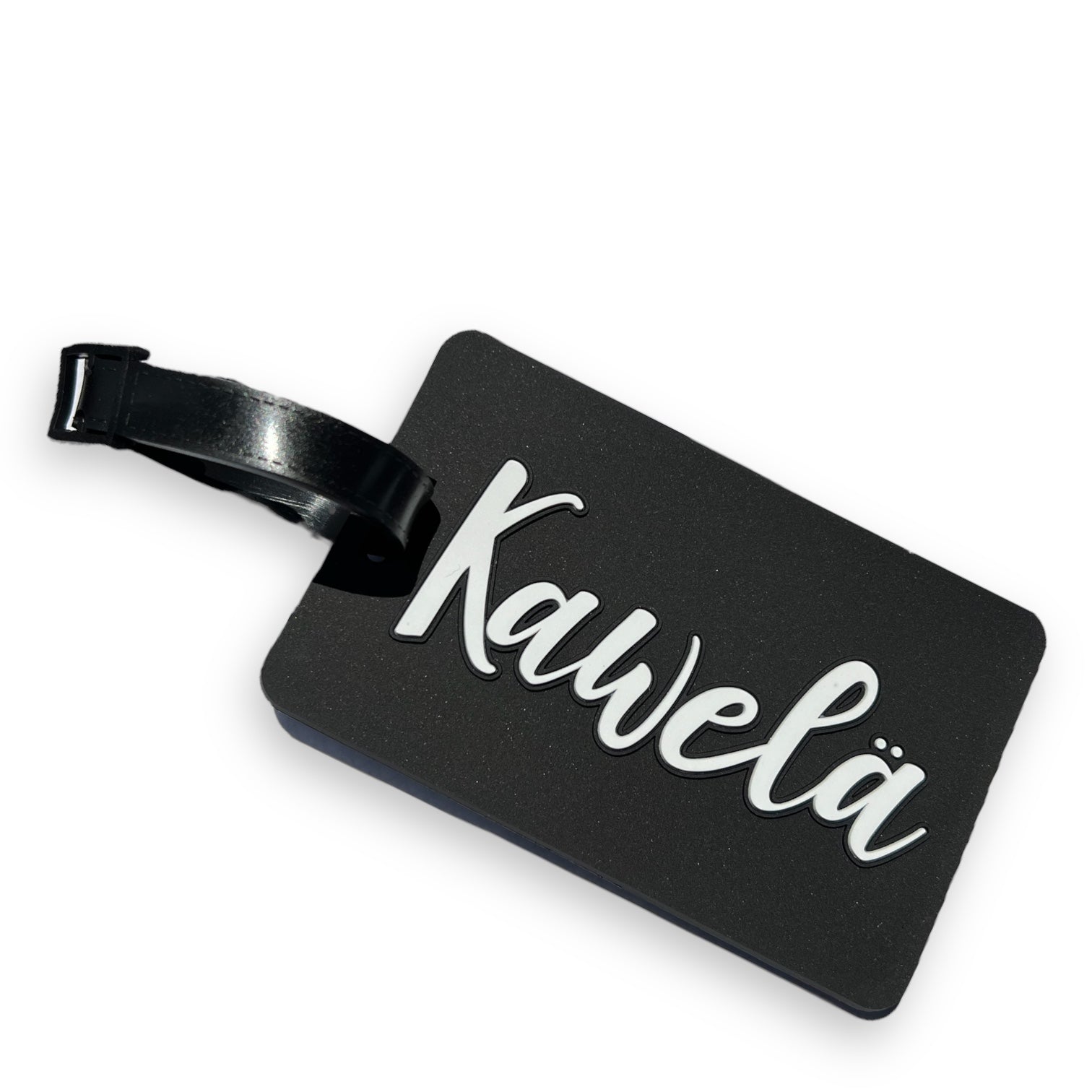 Identificateur de valise KAWELÄ avec étiquette en cuir et motif coloré, attaché à une poignée de valise en bagage.