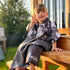 Poncho pour enfants ANDROS TOWN de KAWELÄ, coloré, en tissu imperméable, porté par un enfant dans un environnement urbain.