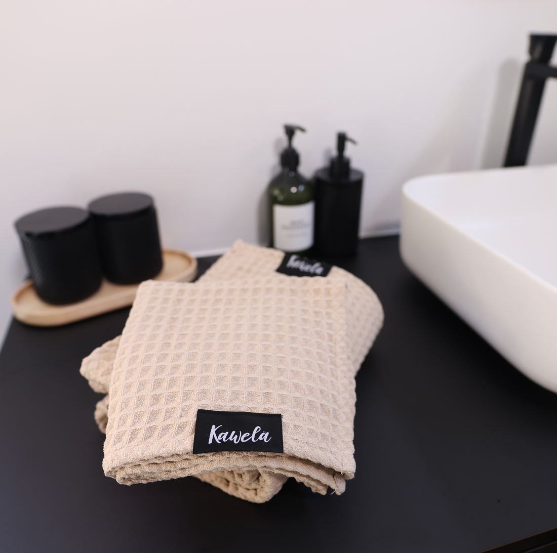 Serviette de bain NUDA de la marque KAWELÄ, en coton doux, avec motif moderne, pliée sur une surface en bois.