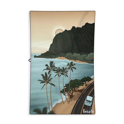 Serviette de plage Coopers Town de la marque Kawelä avec motif coloré, étendue sur le sable.