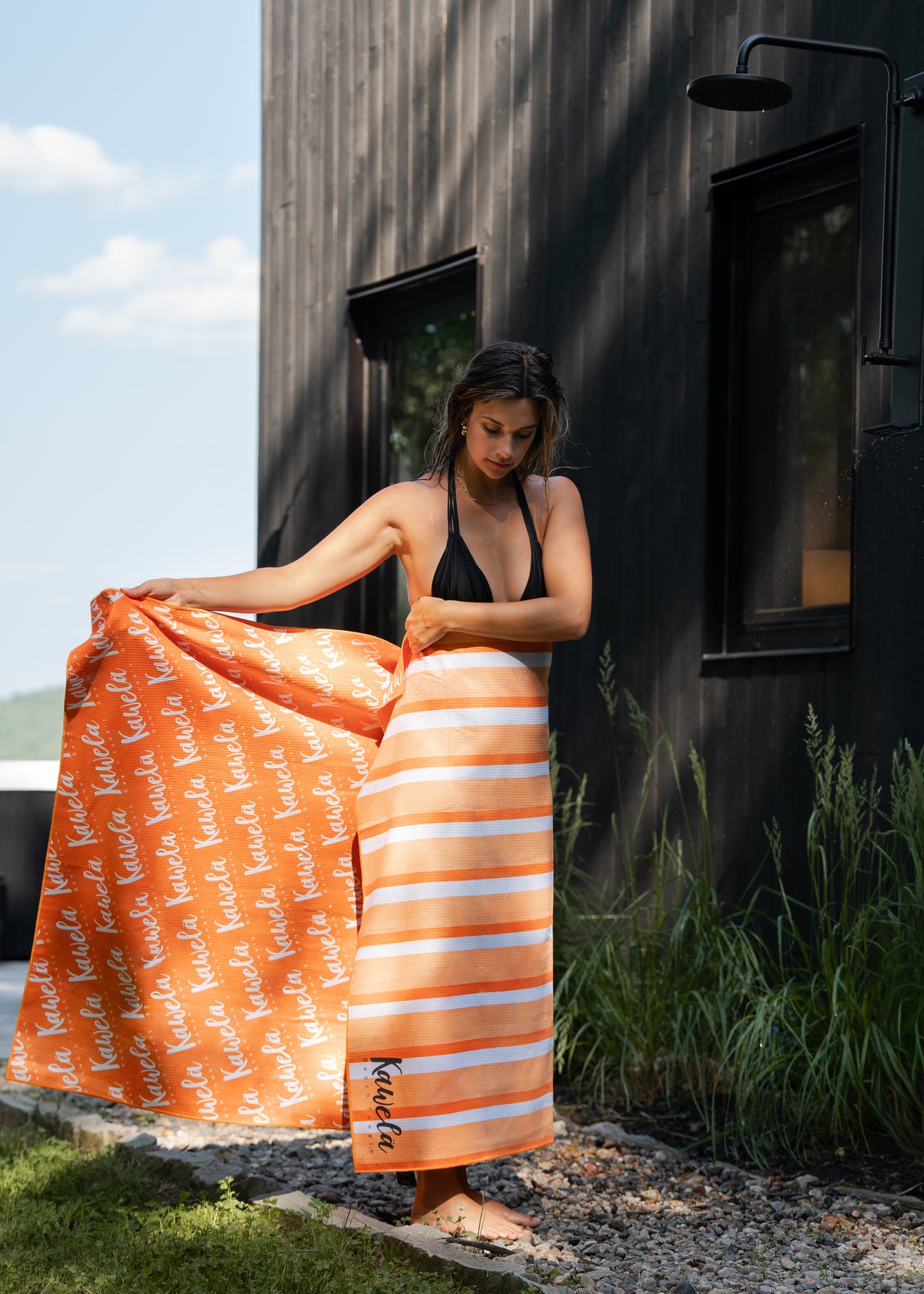 Serviette de plage MARBELLA de KAWELÄ avec motif coloré, étendue sur le sable, idéale pour la baignade et la détente.