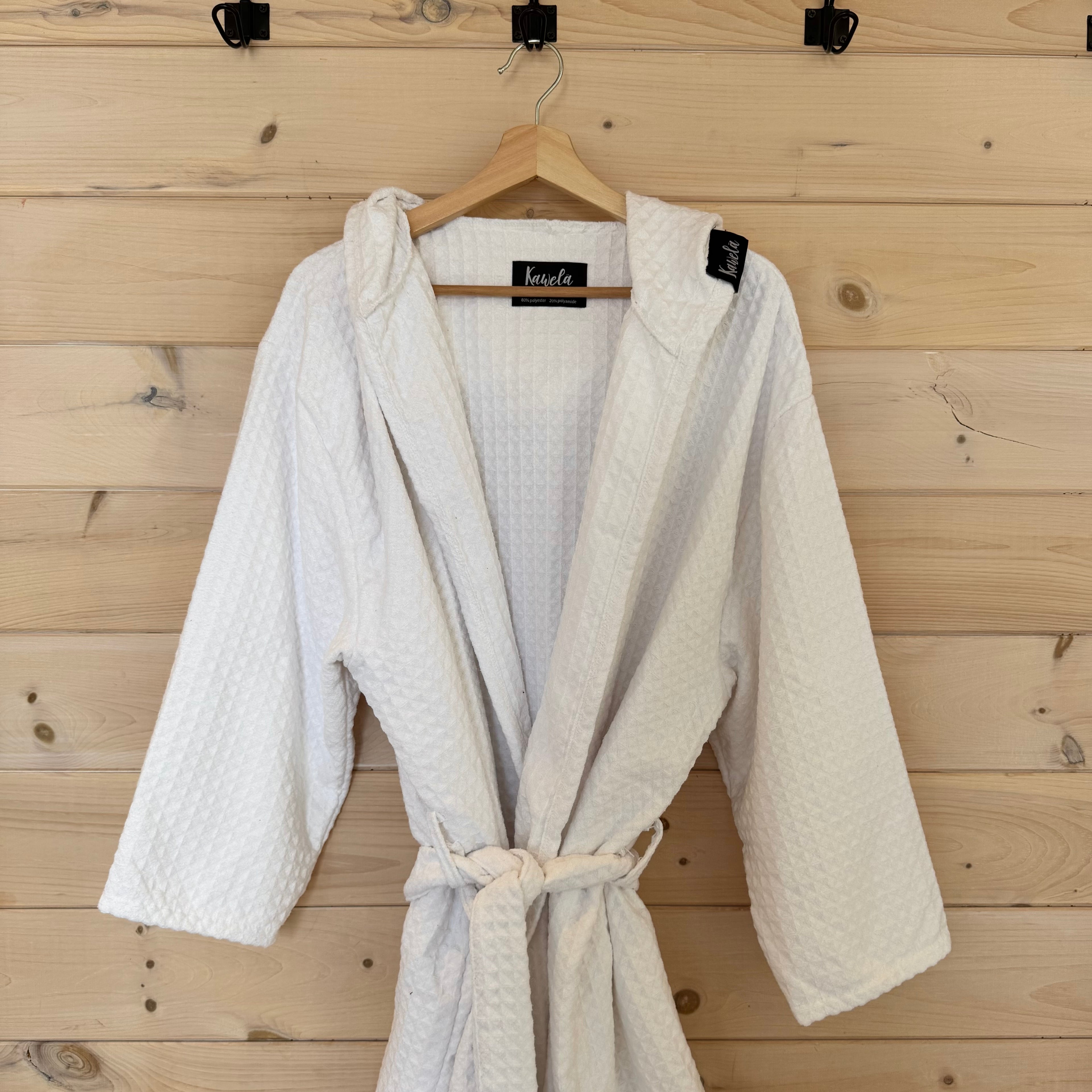 Serviette de bain blanche KAWELÄ WHITEHORSE, en tissu doux et absorbant, pliée sur une surface, pour une utilisation à la maison.