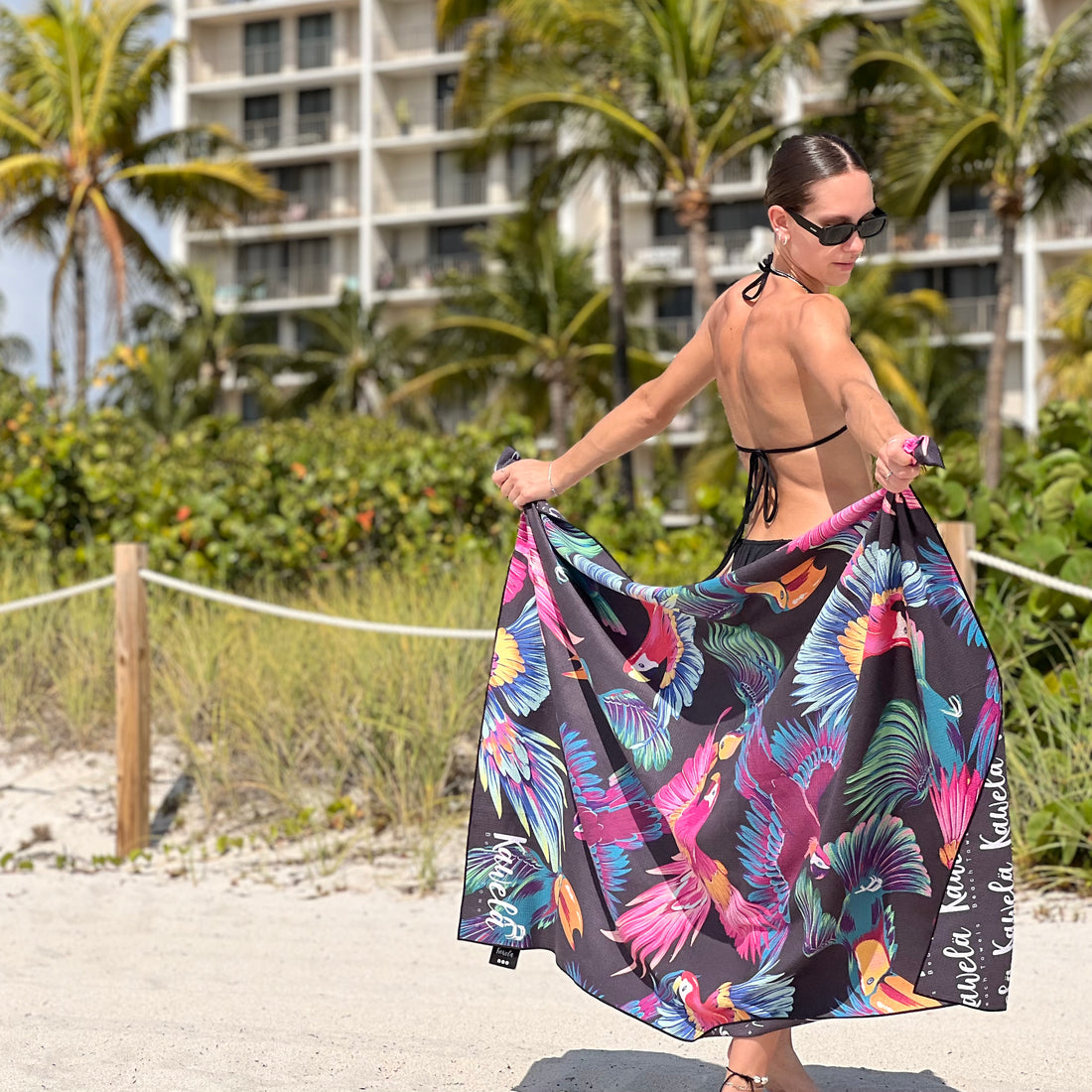 Serviette de plage HIGH ROCK de la marque KAWELÄ, motif coloré et douce, étendue sur le sable.