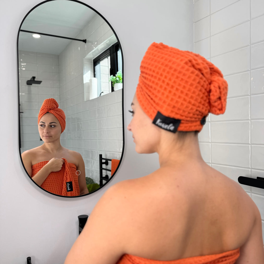 Serviette de bain orange KAWELÄ NARANJA, tissu doux et absorbant, pliée sur une surface blanche.
