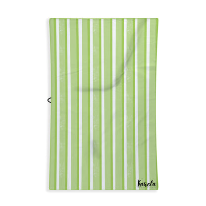 Serviette de plage NIU de la marque KAWELÄ avec motif coloré, étendue sur le sable blanc.