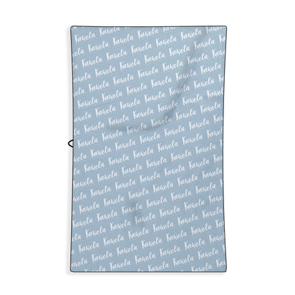 Serviette de plage KAWELÄ Le Marin vue de dos, motif nautique avec rayures bleues et blanches, tissu doux et absorbant.