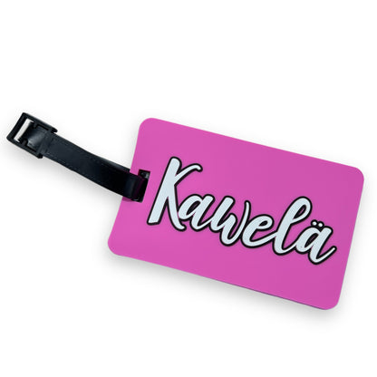 Identificateur de valise KAWELÄ avec étiquette colorée pour identification facile, fixé à une valise en voyage.