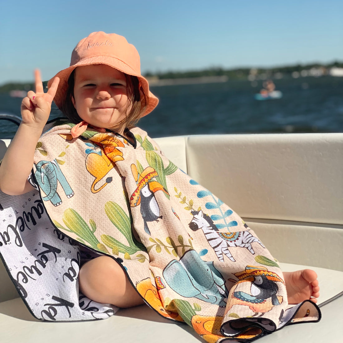 Poncho pour enfants Tijuana de la marque Kawelä, tissu coloré et imprimé, porté par un enfant dans un environnement extérieur.