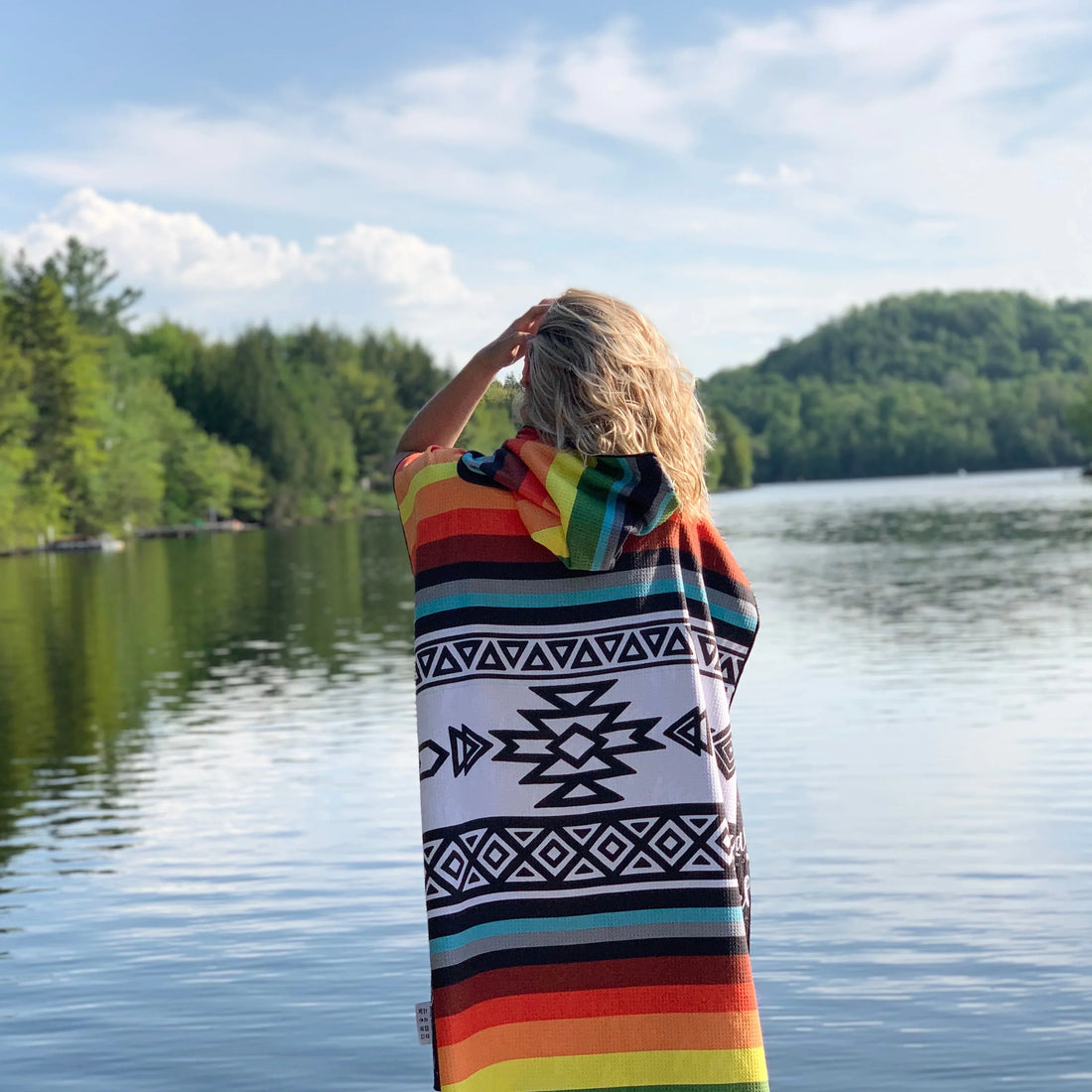 Poncho KAWELÄ TOFINO en tissu léger avec capuche, couleur neutre, porté par une femme dans un environnement extérieur.