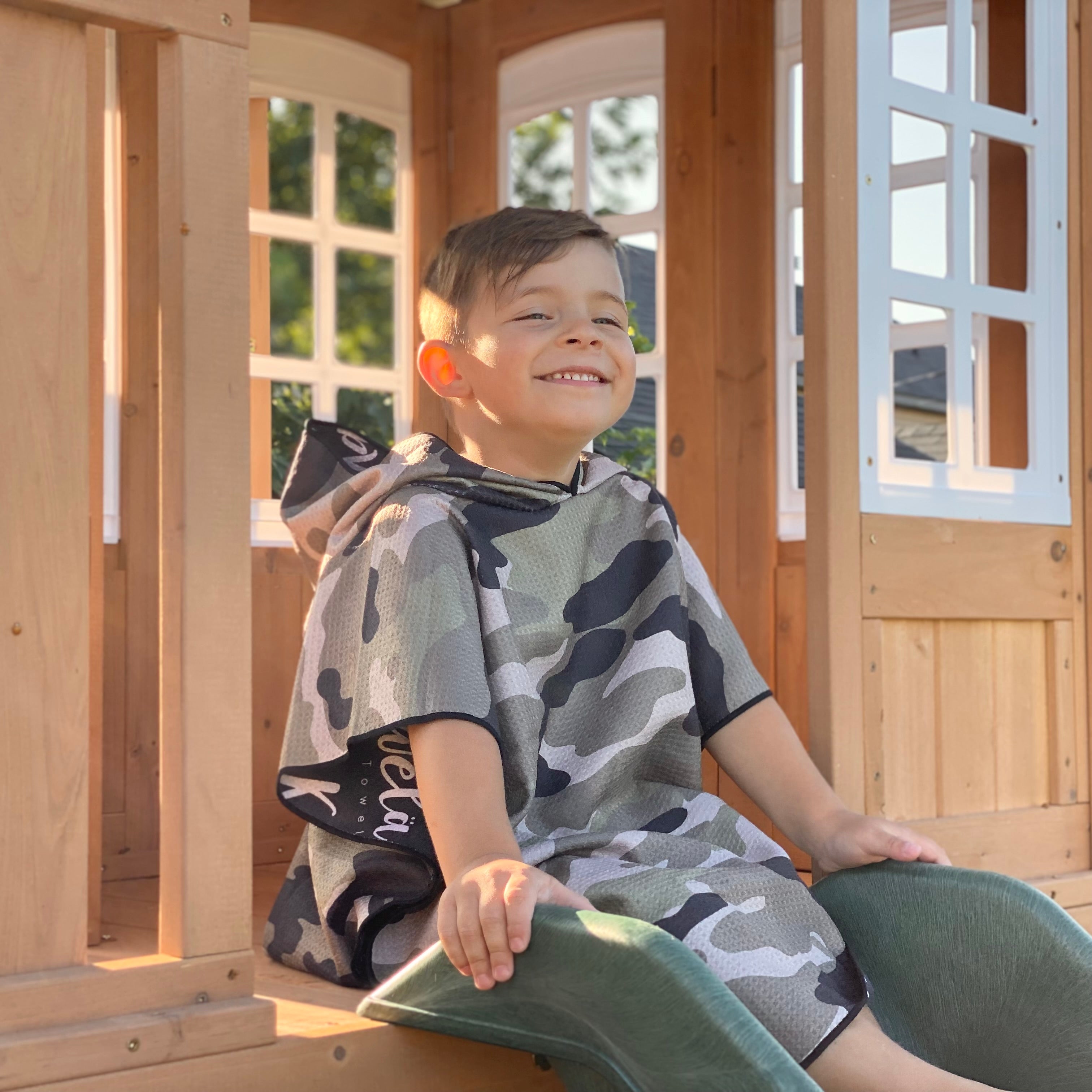 Poncho pour enfants KAWELÄ MAZATLAN en tissu coloré avec motifs, porté par un enfant dans un environnement extérieur.